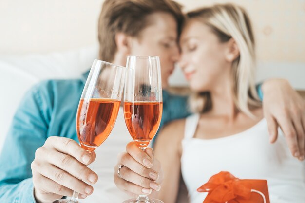 Pareja feliz bebiendo vino en la habitación