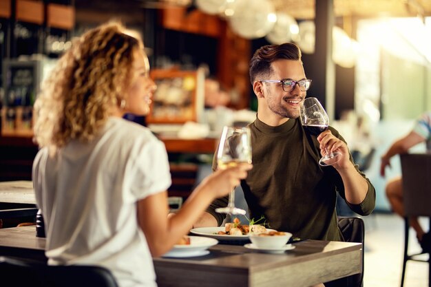 Pareja feliz bebiendo vino mientras almuerza en un restaurante