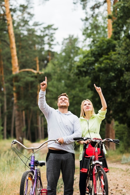 Foto gratuita pareja feliz con bicicletas apuntando hacia arriba