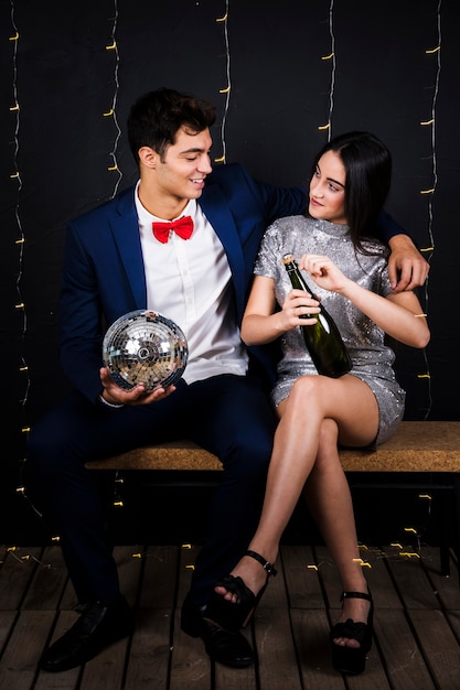 Pareja feliz con bola de discoteca y botella de champagne