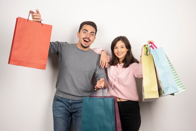 Pareja feliz con bolsas de la compra posando en blanco.