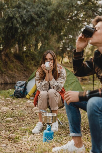 Pareja feliz en el bosque bebiendo de tazas