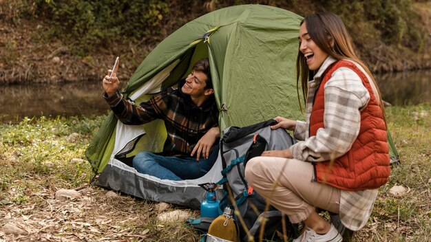 Pareja feliz en el bosque haciendo fotos del uno mismo