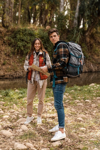 Pareja feliz en el bosque sosteniendo un mapa de tiro largo