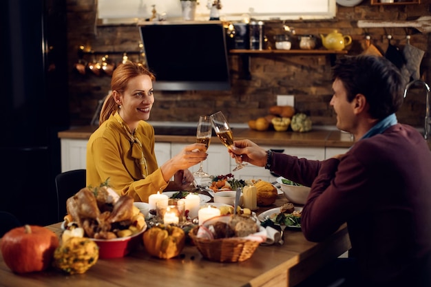 Pareja feliz brindando durante la cena de Acción de Gracias en la mesa de comedor