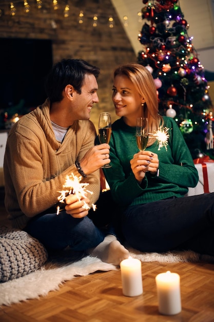 Pareja feliz brindando con champán en la víspera de Navidad en casa