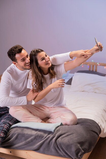 Pareja feliz en la cama tomando selfie