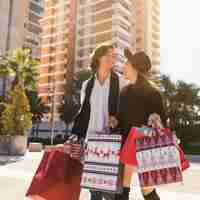 Foto gratuita pareja feliz caminando con bolsas de compras de navidad