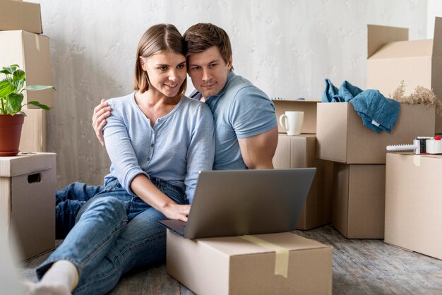 Pareja feliz en casa con cajas y portátil listo para mudarse