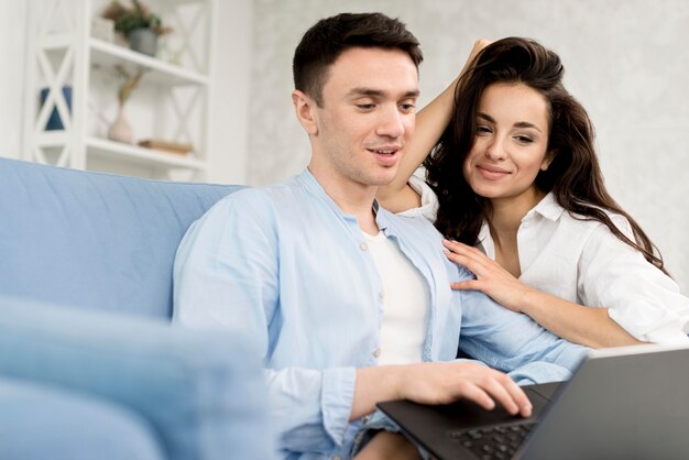 Pareja feliz en casa con laptop