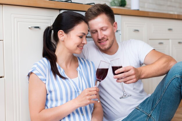 Pareja feliz celebración copas de vino en la cocina