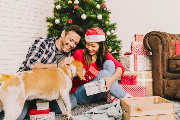 Foto gratuita pareja feliz celebrando navidad con perro