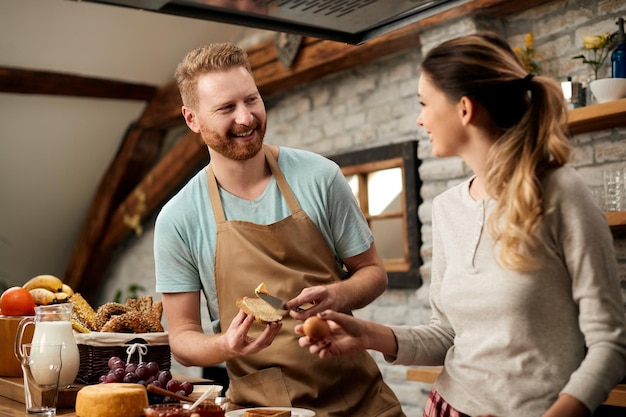 Pareja feliz comunicándose mientras prepara comida en la cocina