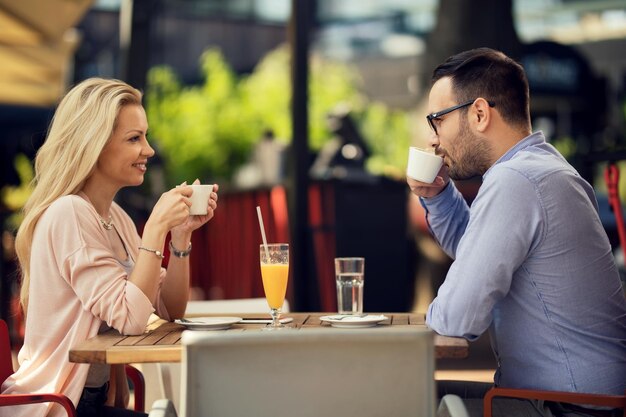 Una pareja feliz comunicándose mientras se relaja en un café y bebe café