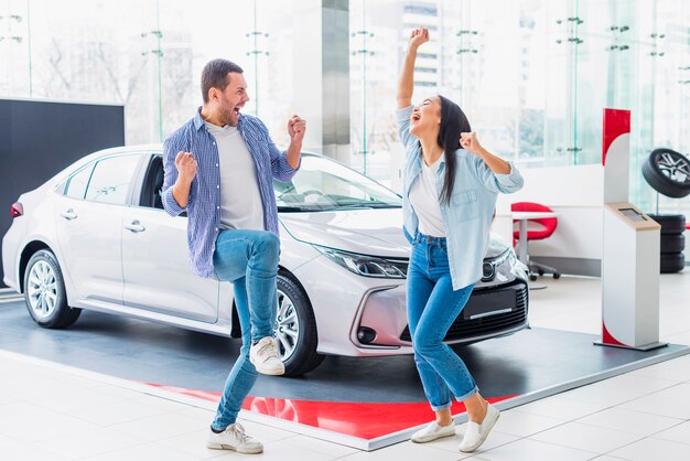 Foto gratuita pareja feliz en concesionario de coches