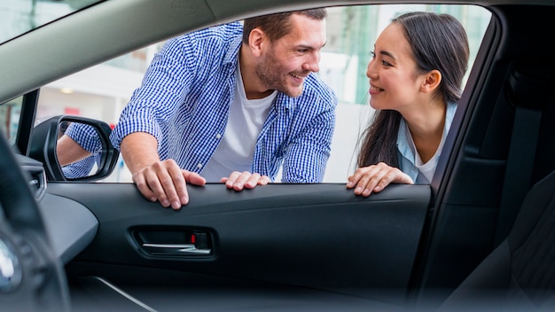 Foto gratuita pareja feliz en concesionario de coches