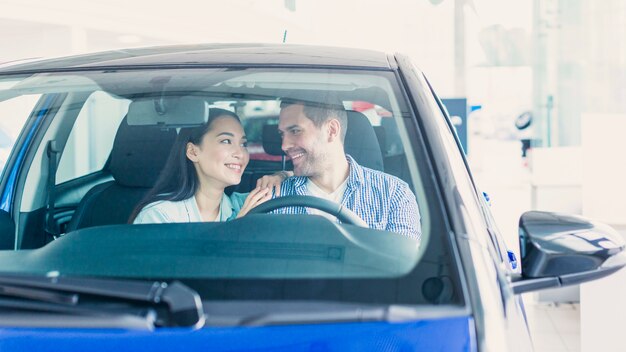 Pareja feliz en concesionario de coches