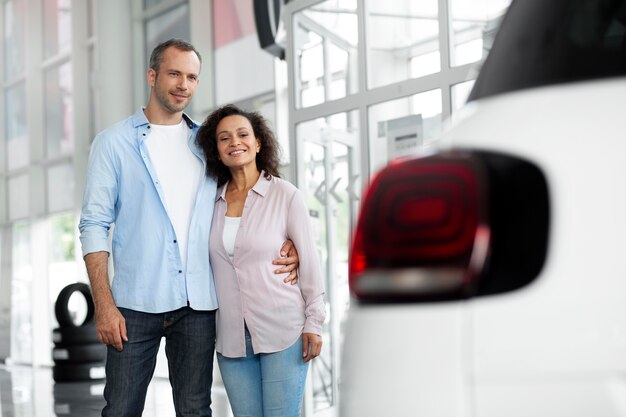 Pareja feliz en concesionario de sala de exposición de coches