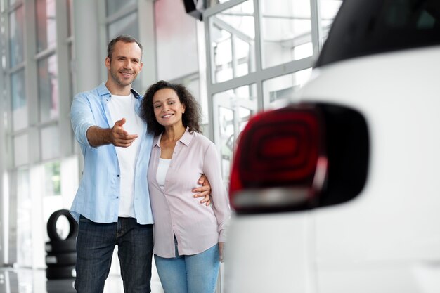 Pareja feliz en concesionario de sala de exposición de coches