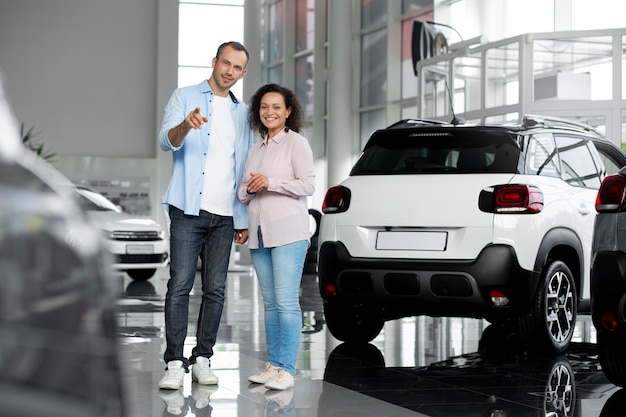 Foto gratuita pareja feliz en concesionario de sala de exposición de coches