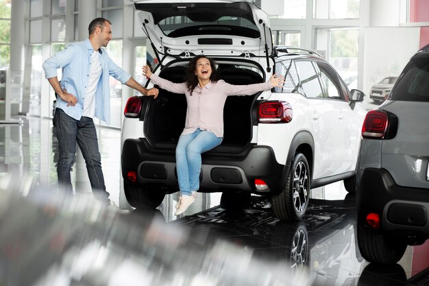 Pareja feliz en concesionario de sala de exposición de coches