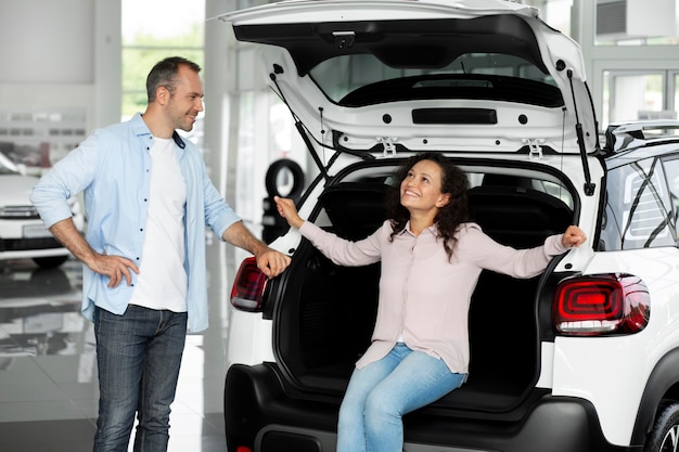 Pareja feliz en concesionario de sala de exposición de coches