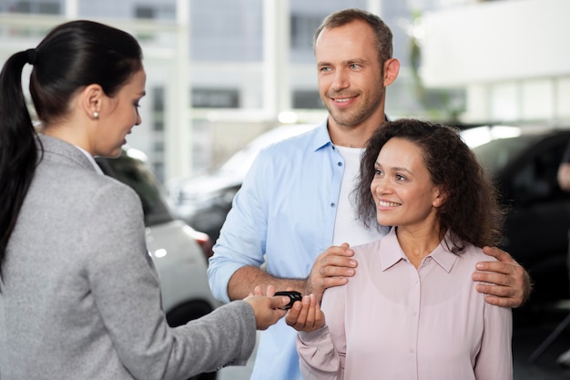 Pareja feliz en concesionario de sala de exposición de coches