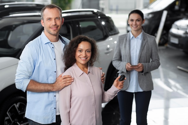 Foto gratuita pareja feliz en concesionario de sala de exposición de coches