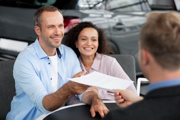 Pareja feliz en concesionario de sala de exposición de coches