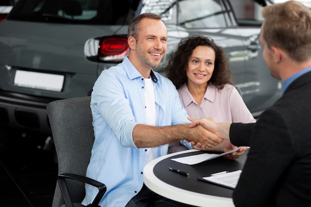 Pareja feliz en concesionario de sala de exposición de coches