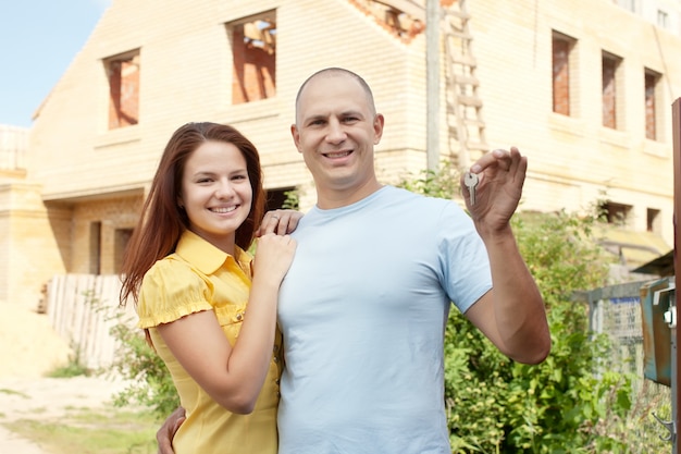 Foto gratuita pareja feliz contra la construcción de nueva casa