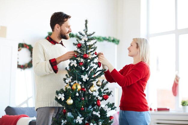 Pareja feliz decorando el árbol de Navidad