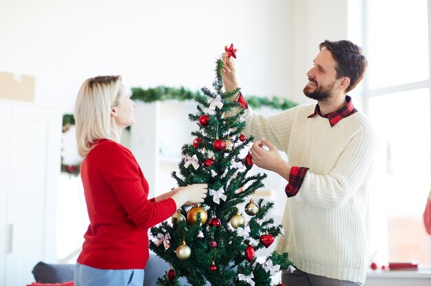 Pareja feliz decorando el árbol de Navidad