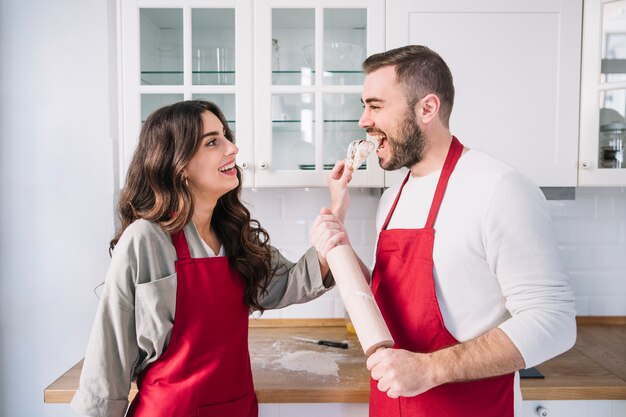 Pareja feliz en delantales en la cocina