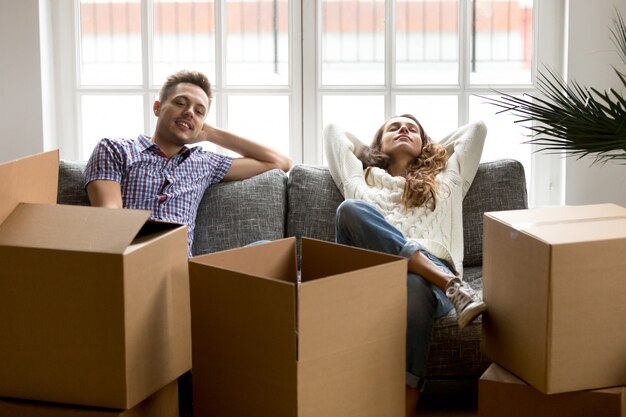 Pareja feliz descansando en el sofá después de mudarse a casa nueva