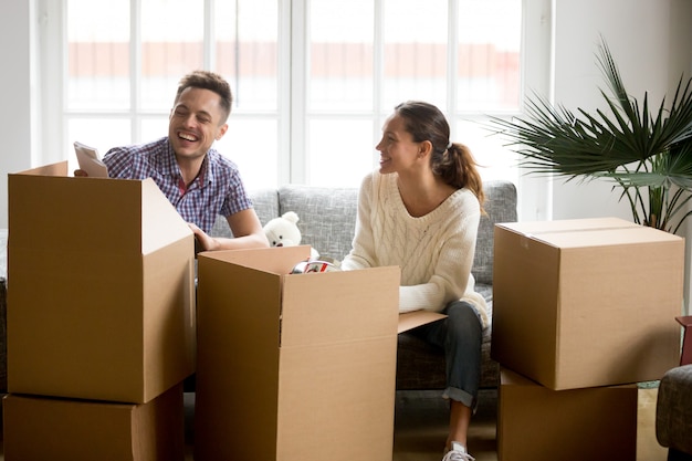 Pareja feliz divirtiéndose riendo desempacando cajas en días en movimiento