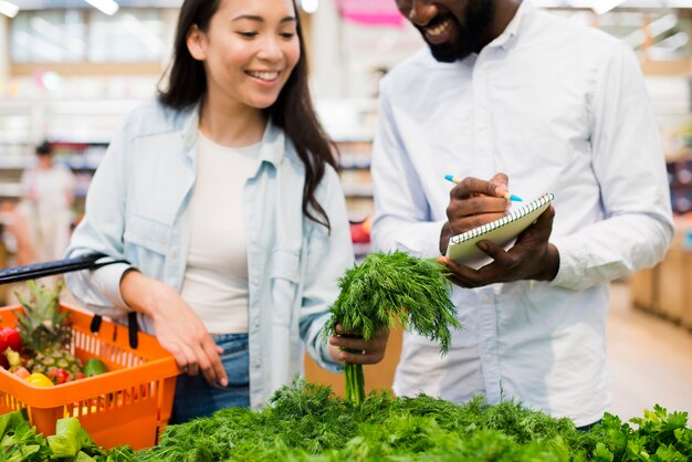 Pareja feliz elegir vegetación en la tienda de comestibles