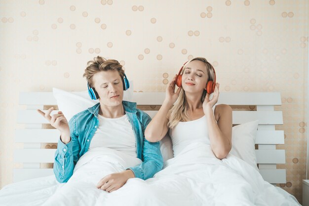 Pareja feliz escuchando la canción en la mañana en el dormitorio