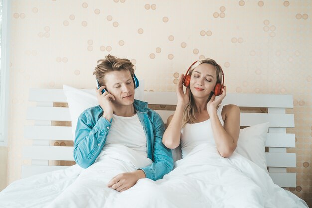 Pareja feliz escuchando la canción en la mañana en el dormitorio