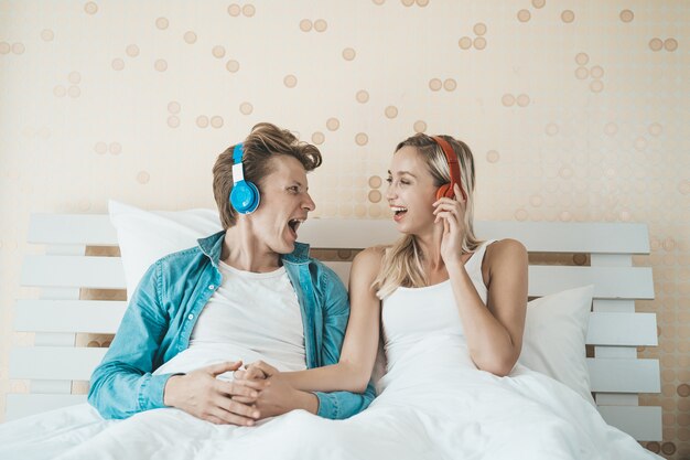 Pareja feliz escuchando la canción en la mañana en el dormitorio