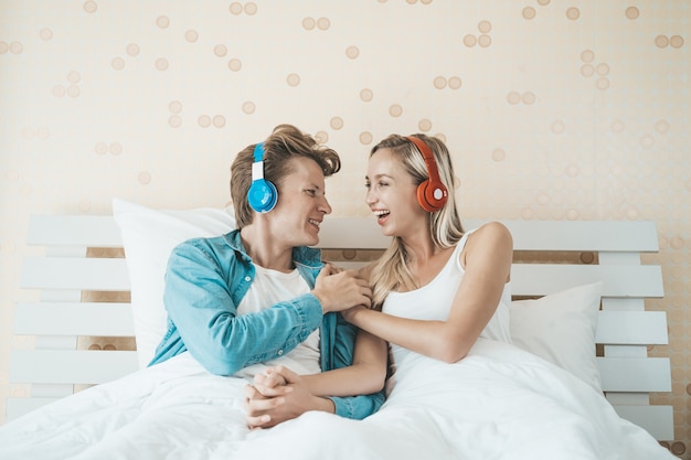 Pareja feliz escuchando la canción en la mañana en el dormitorio