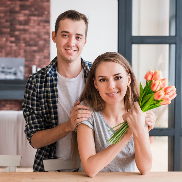 Pareja feliz con flores sonriendo a la cámara