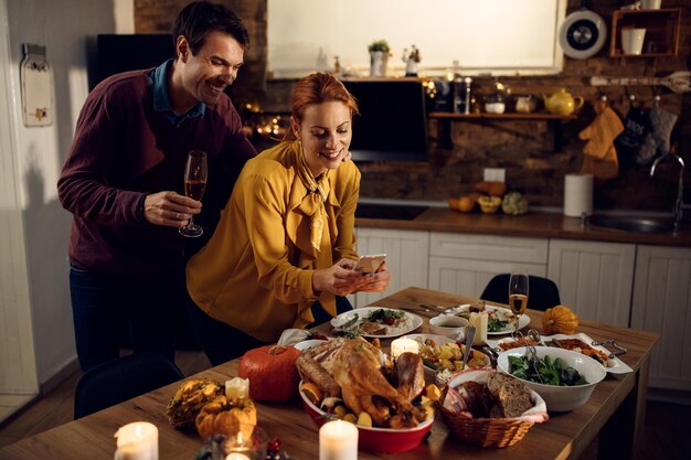 Pareja feliz fotografiando su mesa de comedor en Acción de Gracias