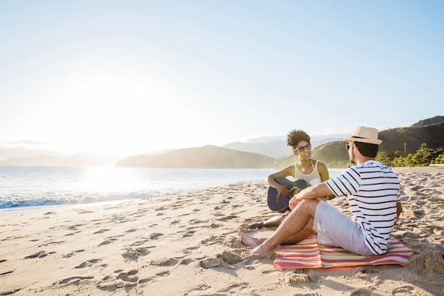 Pareja feliz con guitarra en la playa