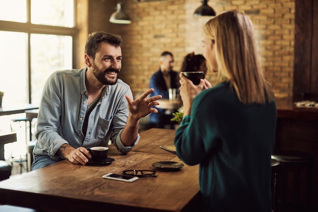 Pareja feliz hablando mientras bebe café en un café