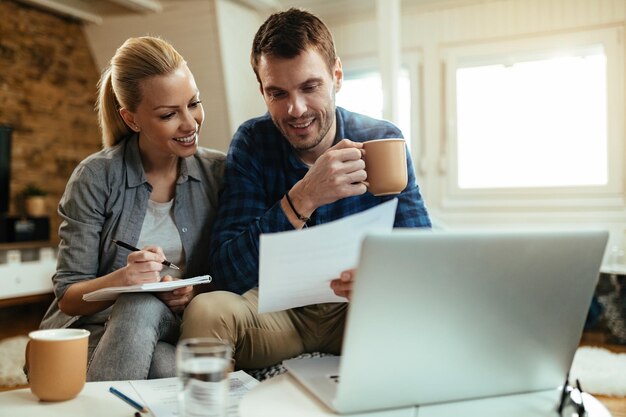 Una pareja feliz haciendo el presupuesto de su hogar mientras revisan las finanzas juntos