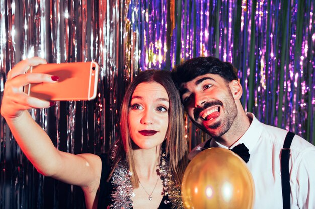 Pareja feliz haciendo un selfie en fiesta de año nuevo