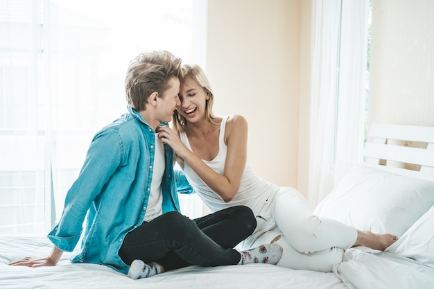 Pareja feliz jugando juntos en el dormitorio