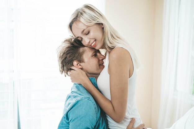 Pareja feliz jugando juntos en el dormitorio