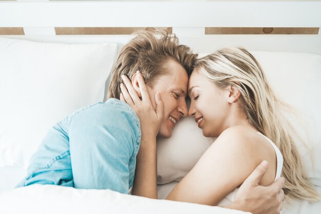 Pareja feliz jugando juntos en el dormitorio